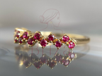 Gold ring with red gemstones on a reflective surface