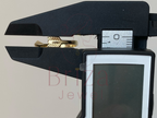 Gold ring being measured with a digital caliper on a white background