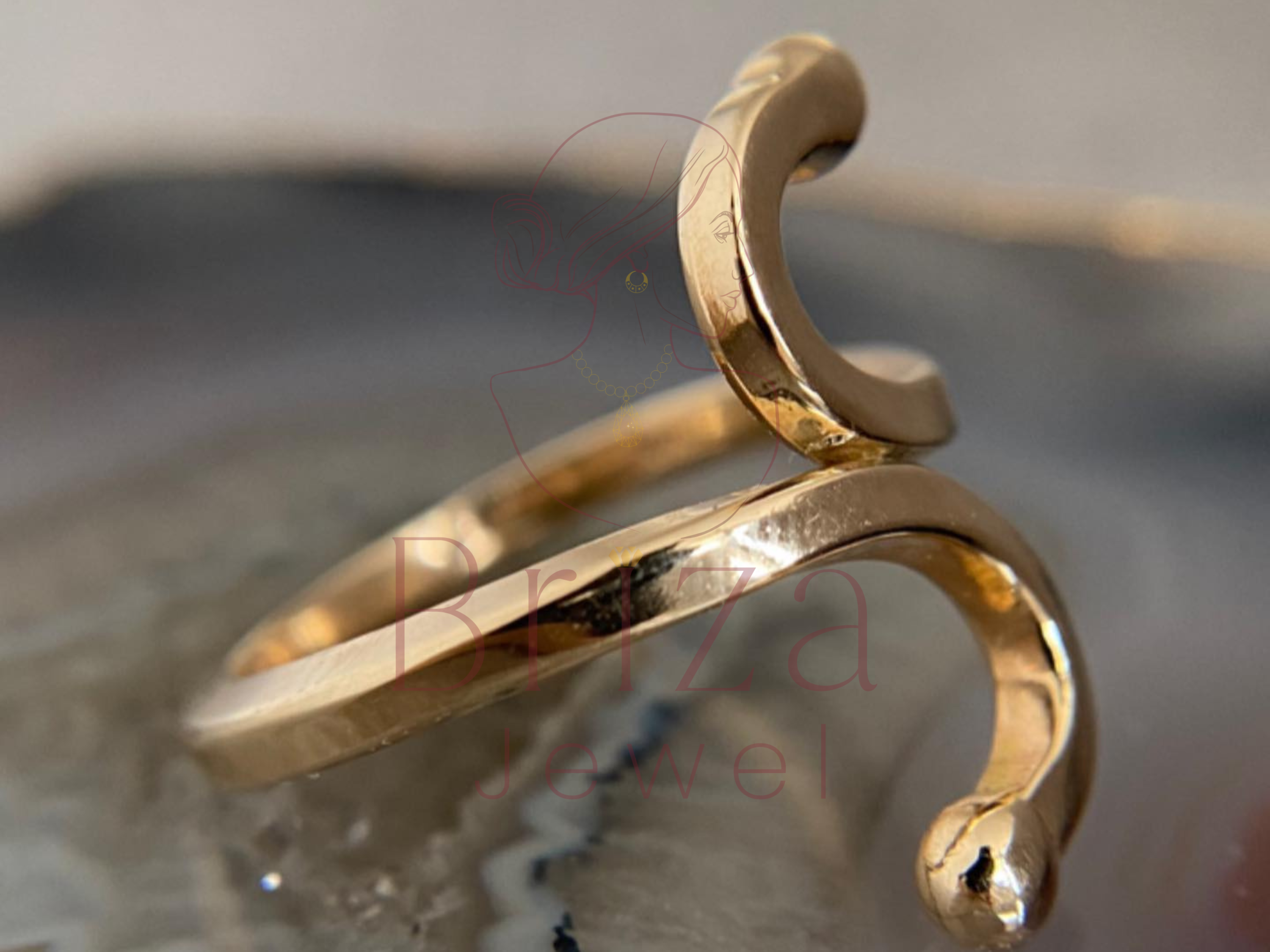 Gold bracelet on a reflective surface with a blurred background