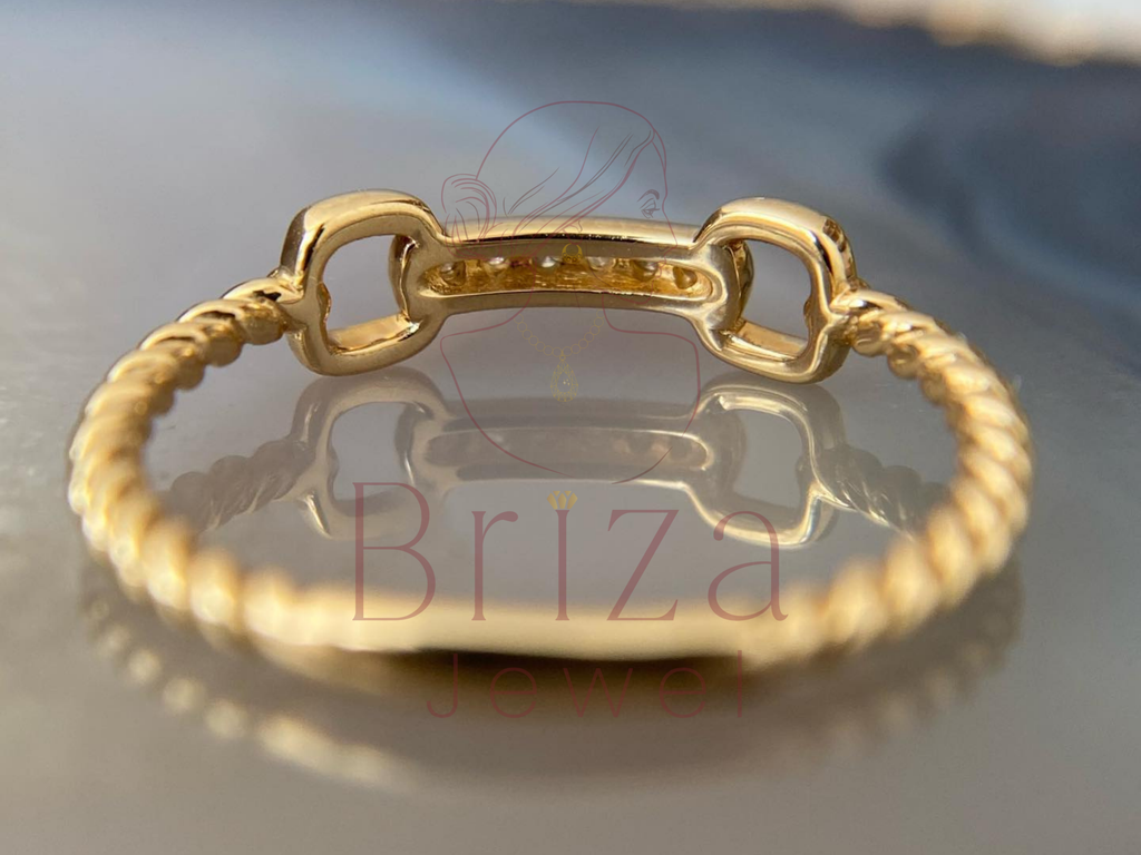 Gold bracelet on a reflective surface with 'Briza' branding.
