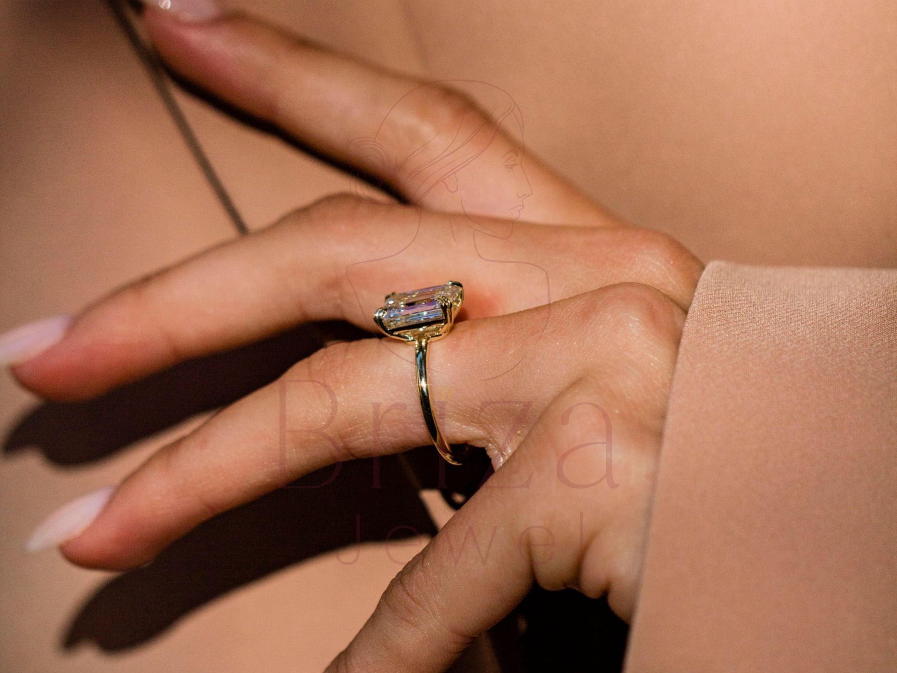 Hand wearing a gold ring with a clear gemstone on a beige background