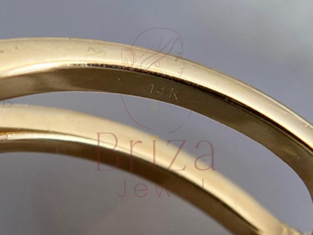 Close-up of a gold ring with 'Briza Jewel' branding on a reflective surface.