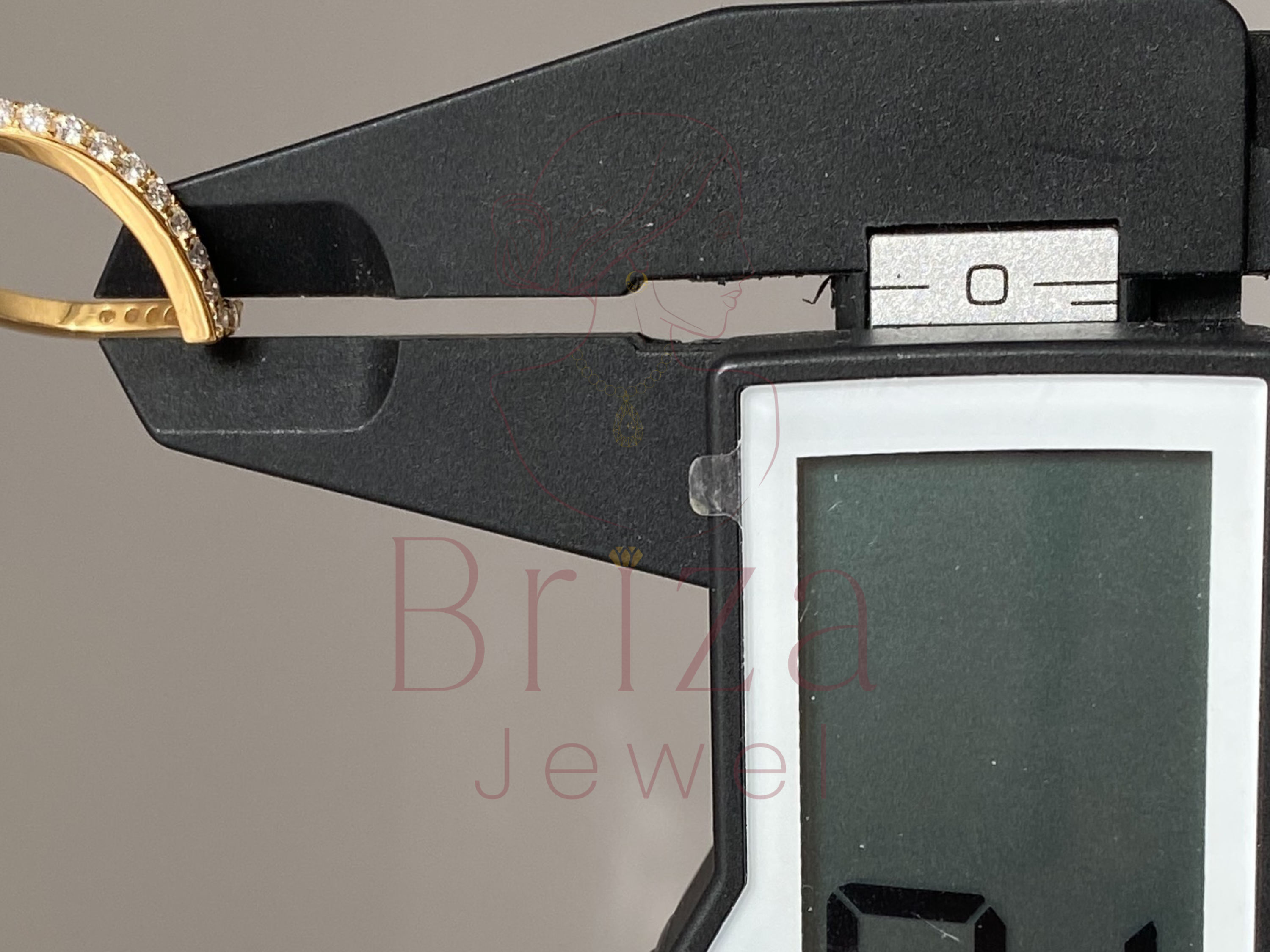 Gold ring being measured with a digital caliper, branded 'Briza Jewelry'.