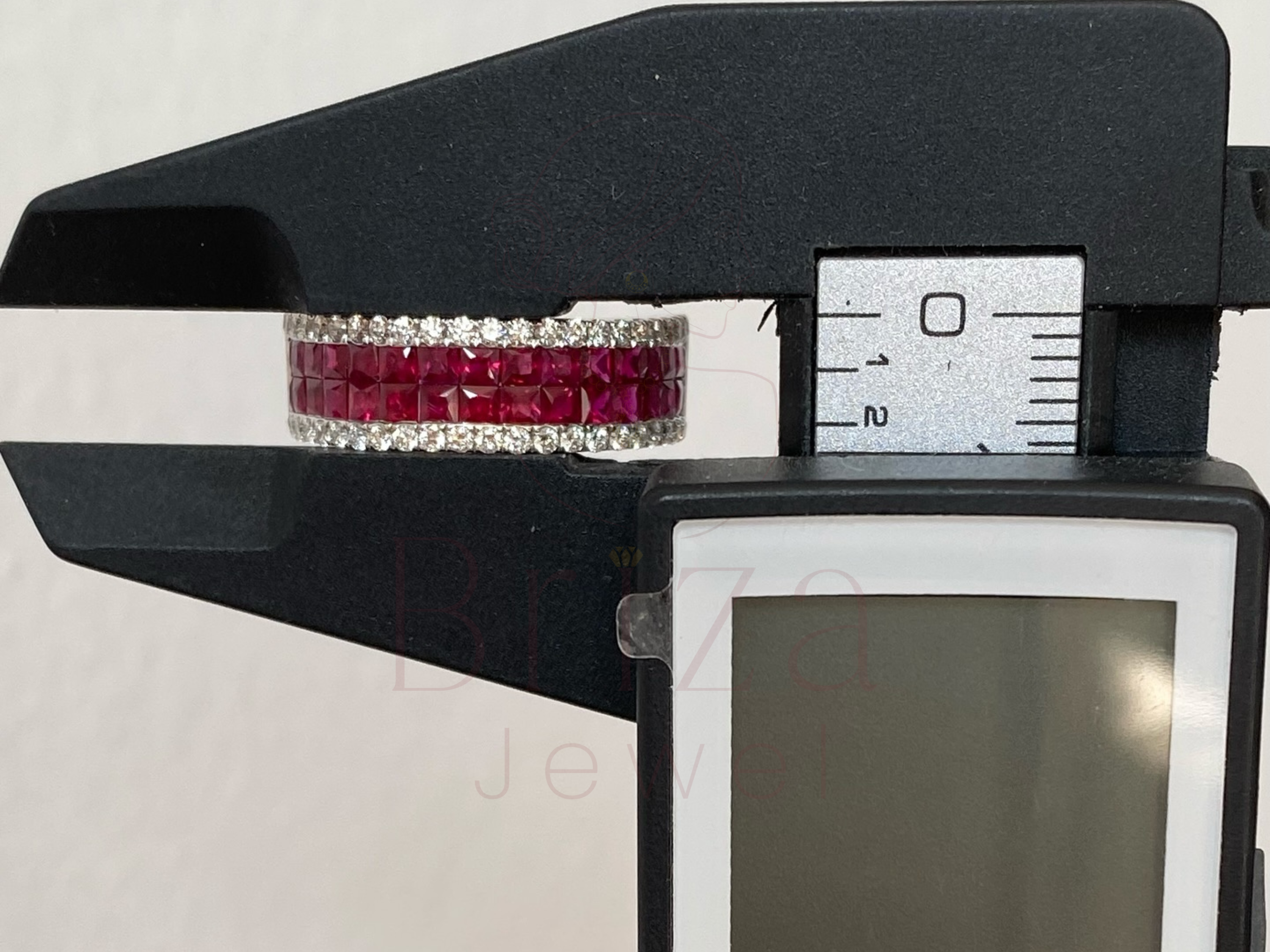 Digital caliper measuring a ruby and diamond bracelet against a white background