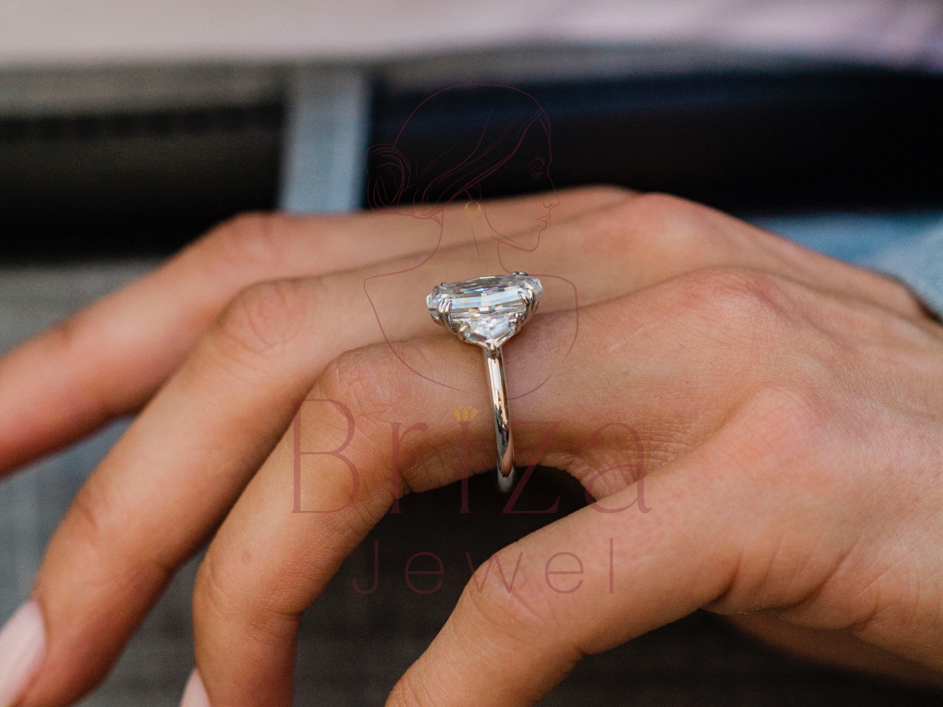 Diamond ring on a finger with 'Briana Jewel' branding.
