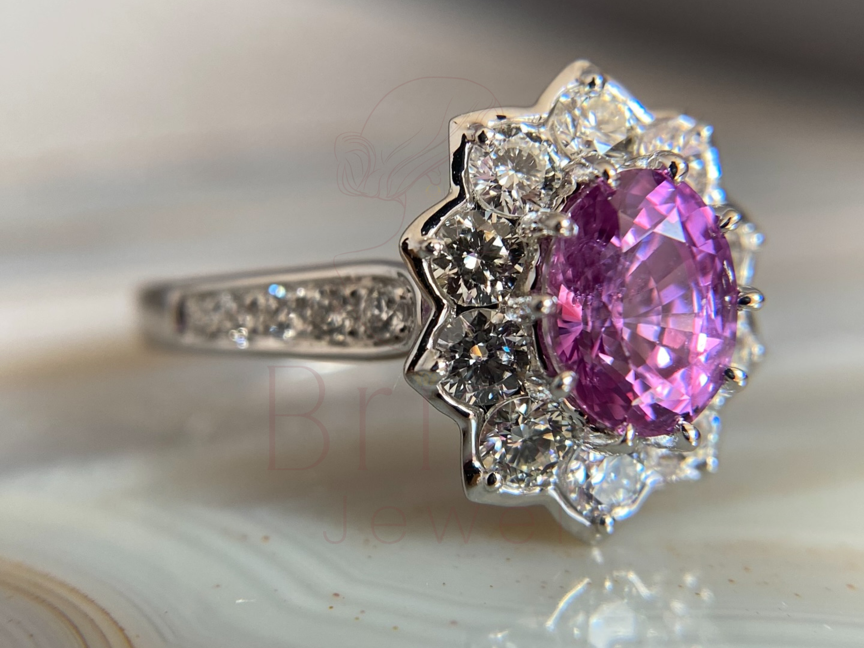 Ring with a pink gemstone and diamond accents on a marble surface