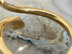 Gold with embedded stones on a textured surface, branded 'Briza Jewel'.