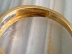 Close-up of a gold ring band with a clear gemstone, showing a 14K stamp on the inner band and a faint 'Briza Jewel' watermark overlay.