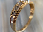 Gold ring with embedded diamonds on a neutral background