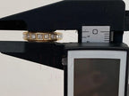 Gold ring with diamonds on a black stand with measurement scale
